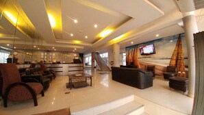 A spacious lobby with a reception desk, seating area, and a large TV screen. - Hotel Libertad (Trujillo)
