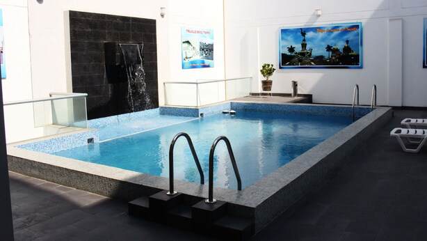 A swimming pool with a tiled border, a water feature, and a poster on the wall. - Hotel Libertad (Trujillo)