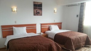 A hotel room with two beds, a wooden headboard, a painting on the wall, and a telephone on the nightstand. - Hotel Libertad (Trujillo)