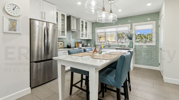 A modern kitchen with stainless steel appliances, a central island with bar stools, and pendant lighting.