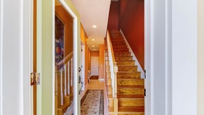 Una escalera de madera con barandilla, que lleva a una habitación con una puerta y una ventana.