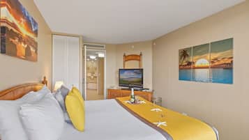 Una habitación de hotel con cama, televisión y pinturas de atardeceres.