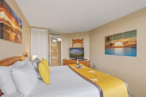 Una habitación de hotel con cama, televisión y pinturas de atardeceres.