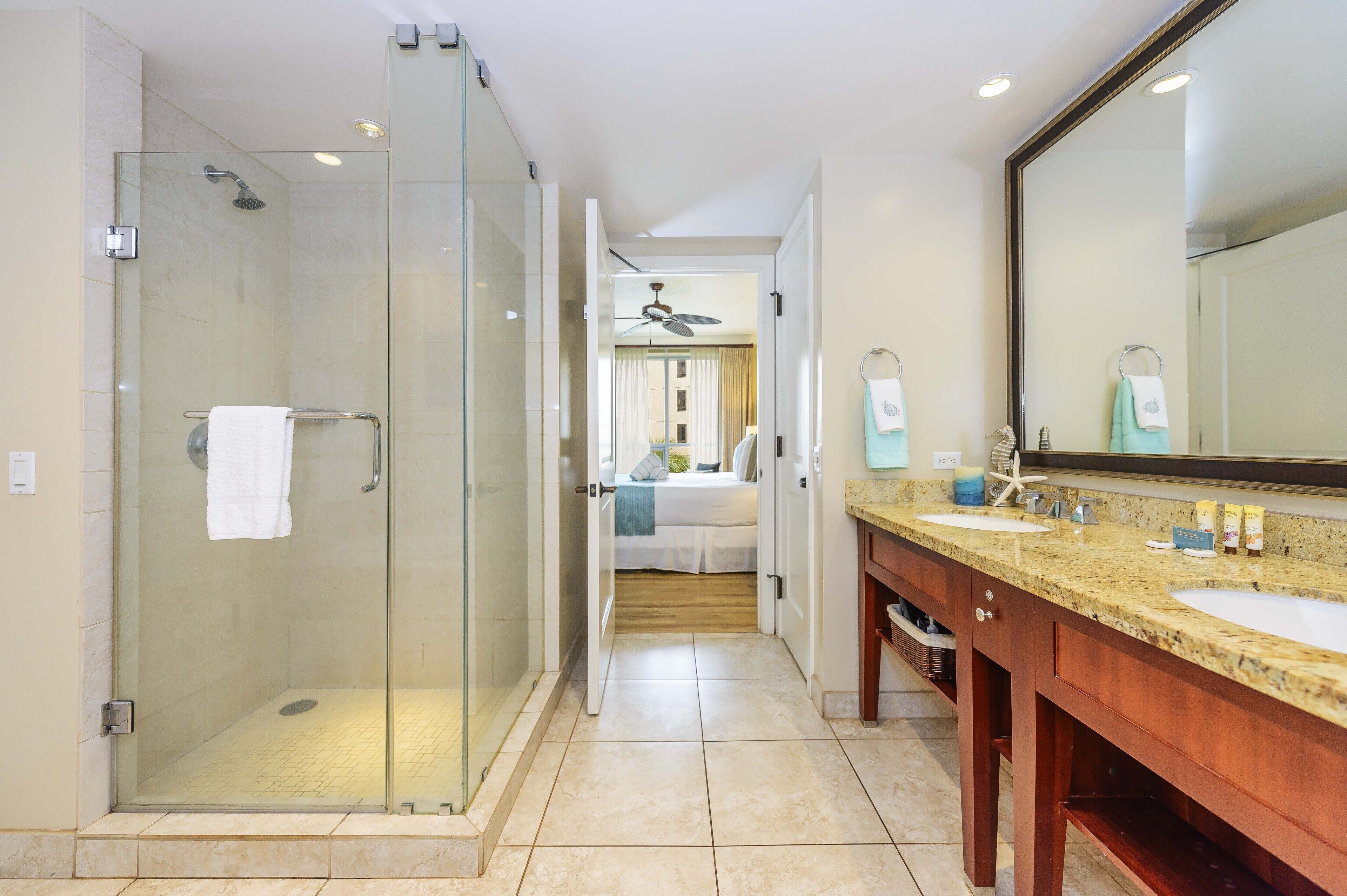A modern bathroom with a glass-enclosed shower, a vanity with a granite countertop, and a large mirror.