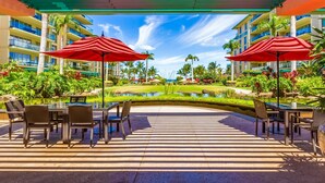 A covered outdoor area with tables and chairs, a small water feature, and a view of a hotel building.