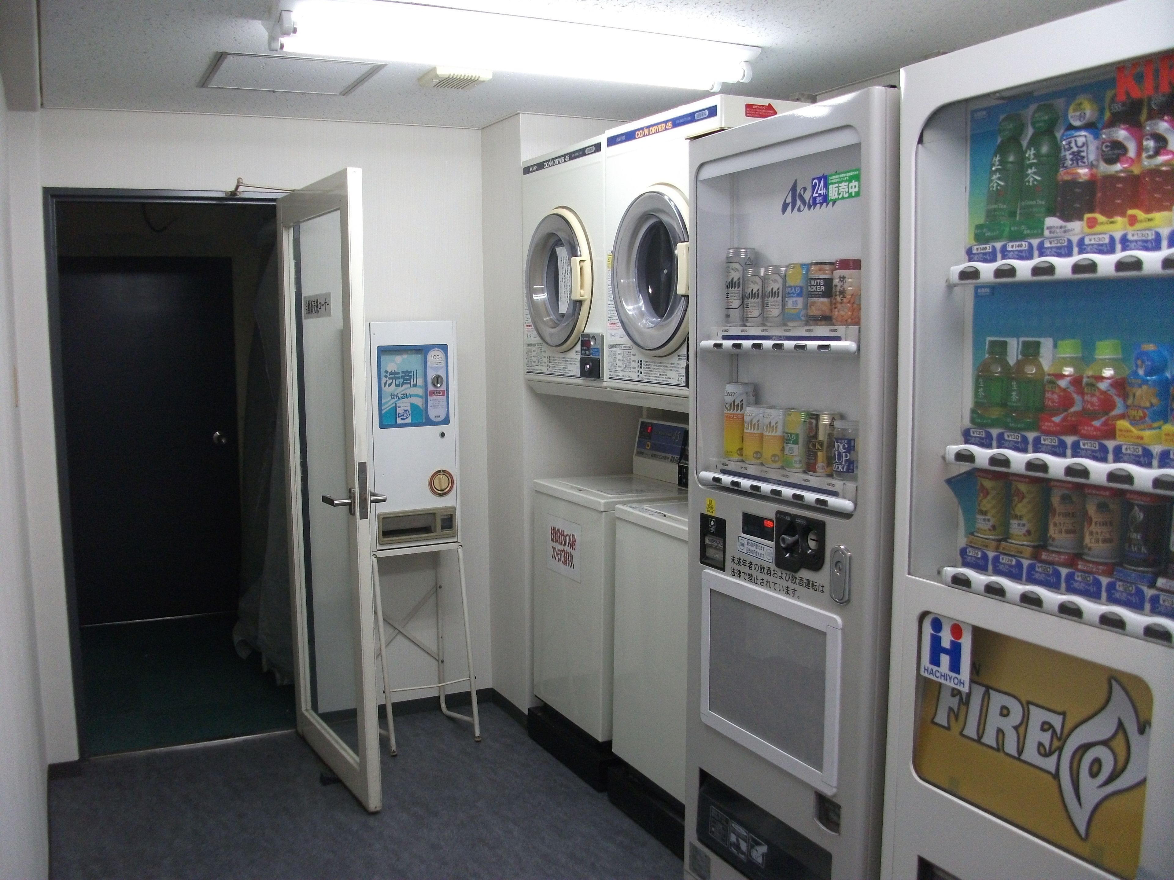 A laundry room with a washing machine, dryer, and vending machines.