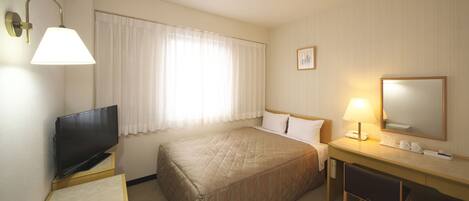 A hotel room with a bed, a desk, a television, a lamp, and a mirror.
