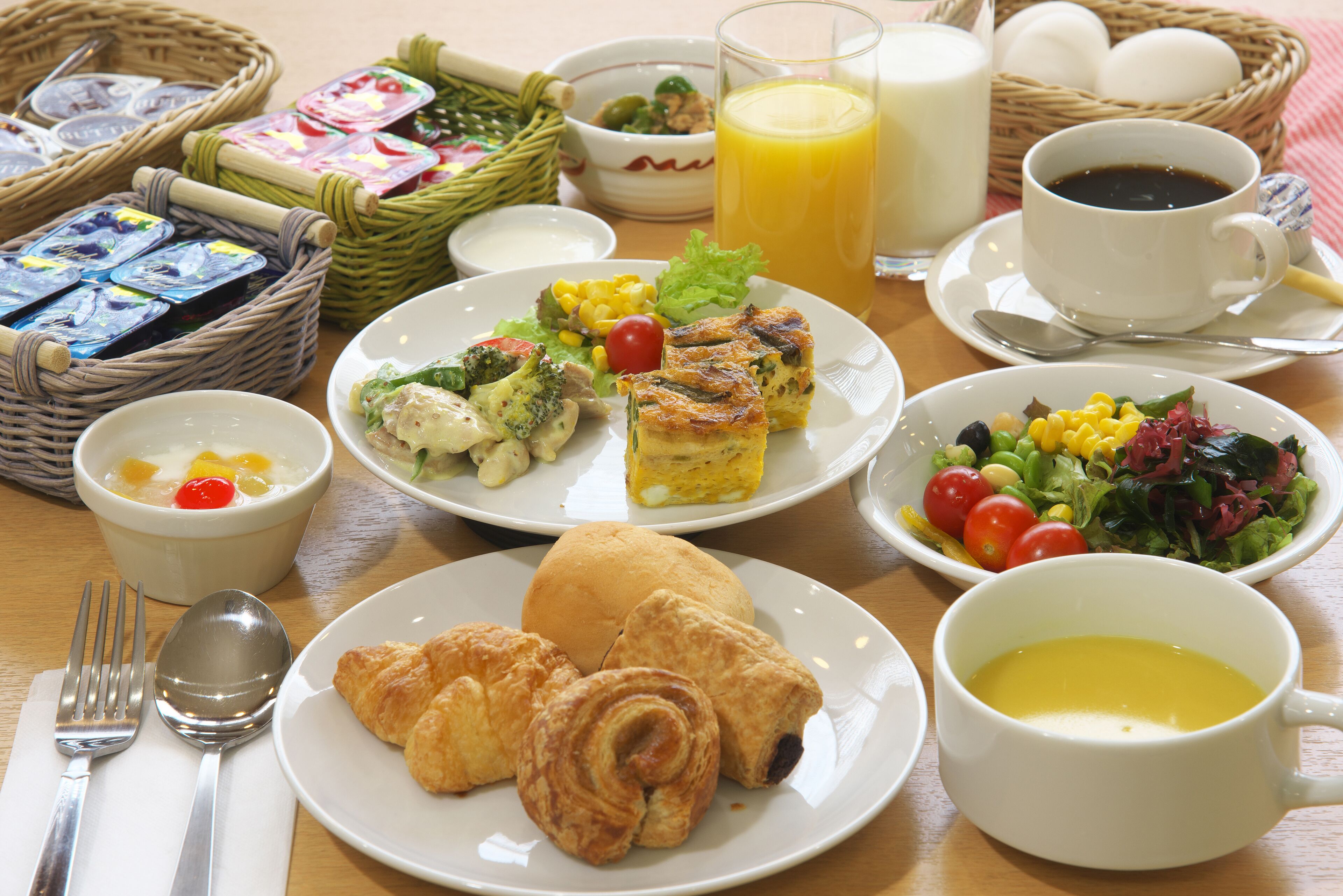 A breakfast setting with plates of food, a glass of orange juice, and a cup of coffee.