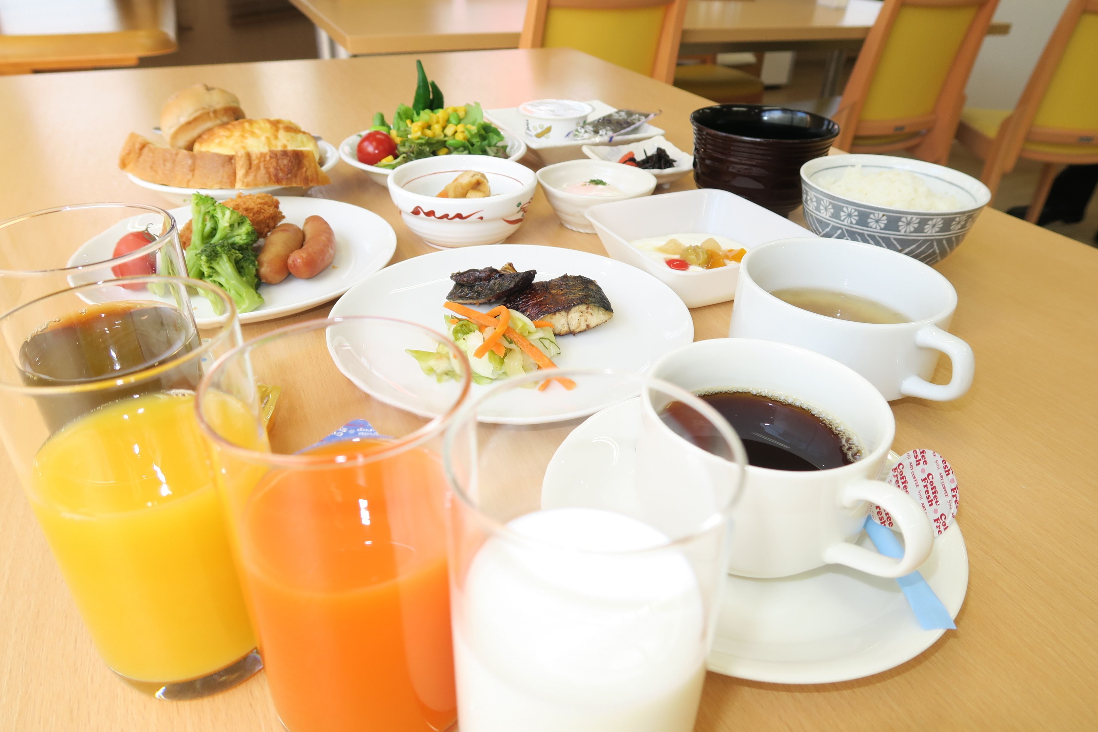 A breakfast table with various dishes, drinks, and a cup with a tea bag.