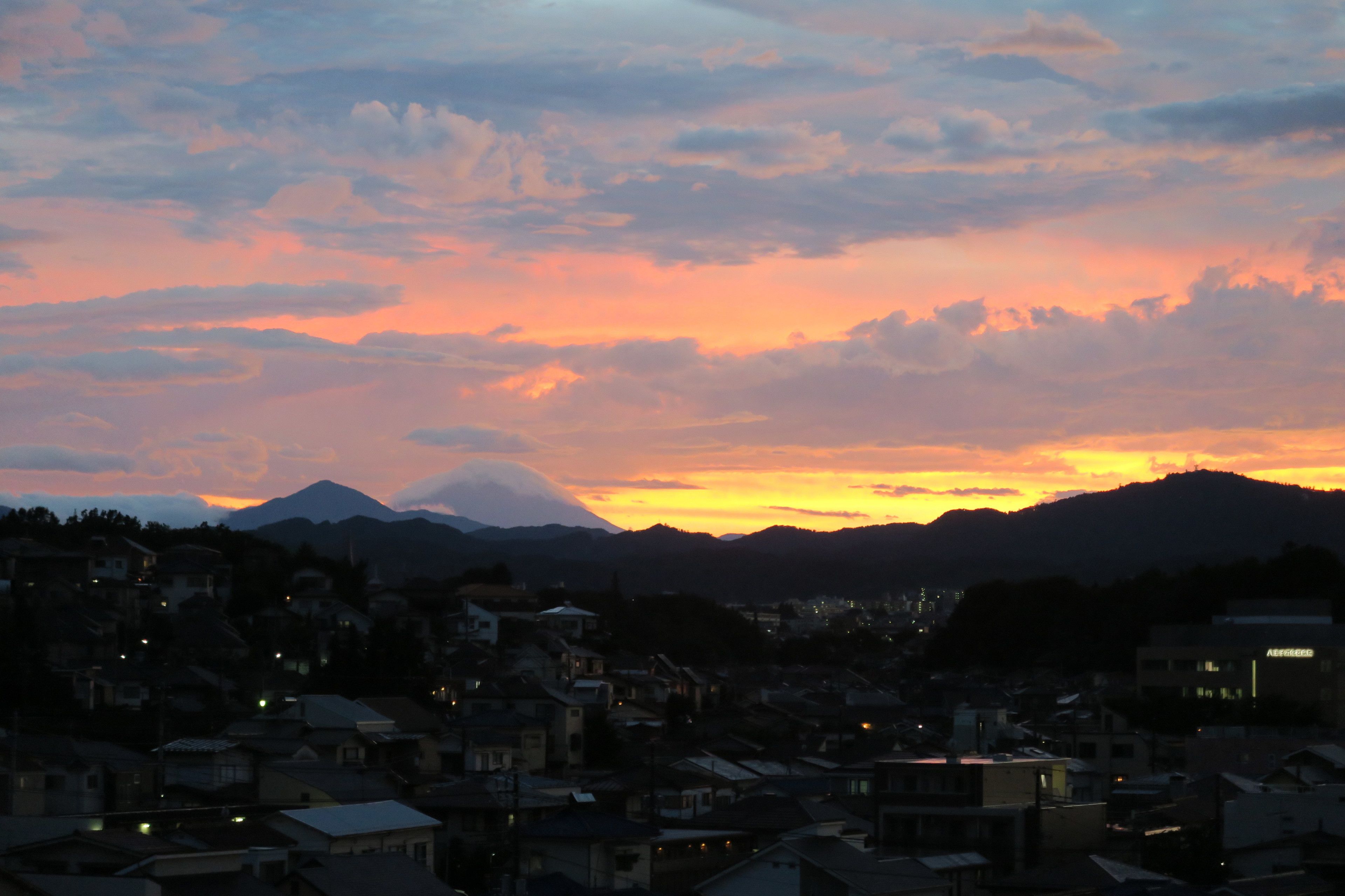 Una cordillera al atardecer con un pueblo en primer plano.