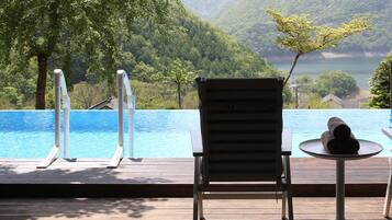 A poolside area with a wooden deck, a lounge chair, and a small table with a towel.