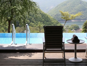 A poolside area with a wooden deck, a lounge chair, and a small table with a towel. - Penatess Pool Villa (Chungju)