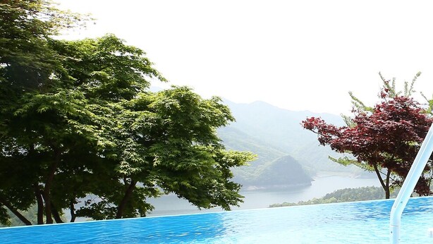 Una piscina con vistas a montañas y árboles.