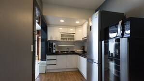 Una cocina moderna con armarios blancos, un refrigerador de acero inoxidable y piso de madera.