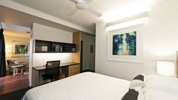 Une chambre d’hôtel avec un lit, un bureau, une chaise et un tableau au mur.