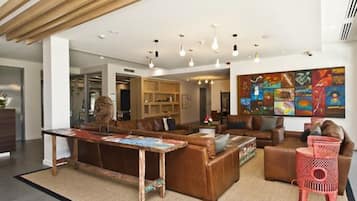 A modern living room with a wooden ceiling, a large abstract painting, and a red chair.