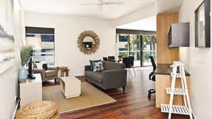 A modern living room with a gray sofa, a coffee table, and a white side table. There is a large mirror on the wall and a ceiling fan. - St Catherine's on Park (Crawley)