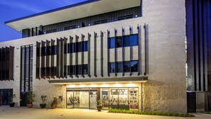 A modern building with a curved facade, large windows, and a well-lit entrance with potted plants. - St Catherine's on Park (Crawley)
