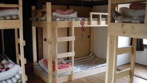 A room with three bunk beds, each with a mattress and pillows.