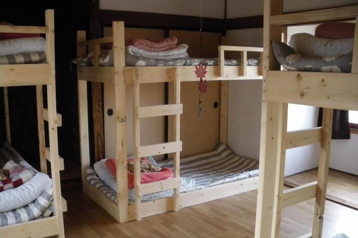 A room with three bunk beds, each with a mattress and pillows.