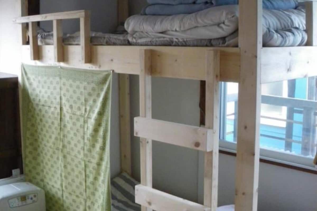 A bunk bed room with a window, a washing machine, and a patterned curtain.