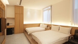 Habitación de hotel con dos camas, un armario de madera, un escritorio pequeño con una tetera y un televisor.