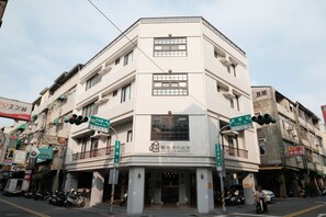A corner building with a sign for 'Journey Hostel' and multiple signs for local businesses.