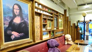 A room with a large framed artwork on the wall, a red cushioned bench, and wooden tables with chairs. - House 123 Lan (Tainan)