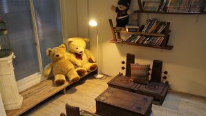 A cozy room with a large teddy bear, a bookshelf, and a small table. - House 123 Lan (Tainan)