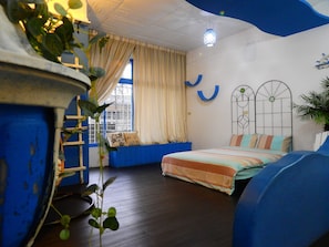 A bedroom with a bed, a window with curtains, a blue wall, and a hanging light fixture. - House 123 Lan (Tainan)