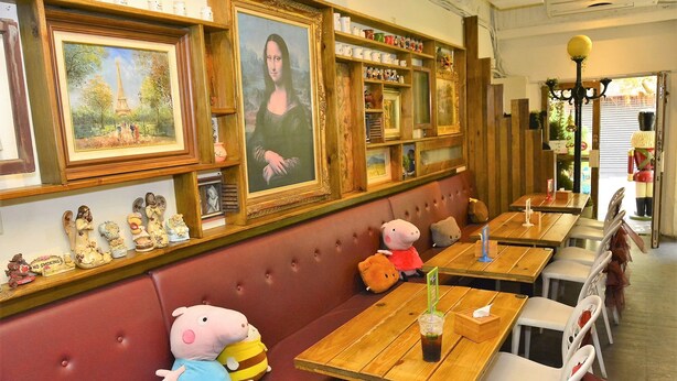 A restaurant with wooden tables, cushioned booths, and wall-mounted paintings. - House 123 Lan (Tainan)