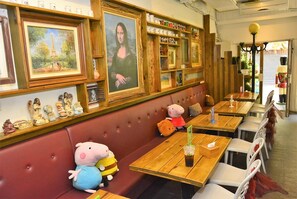 A restaurant with wooden tables, cushioned booths, and wall-mounted paintings. - House 123 Lan (Tainan)