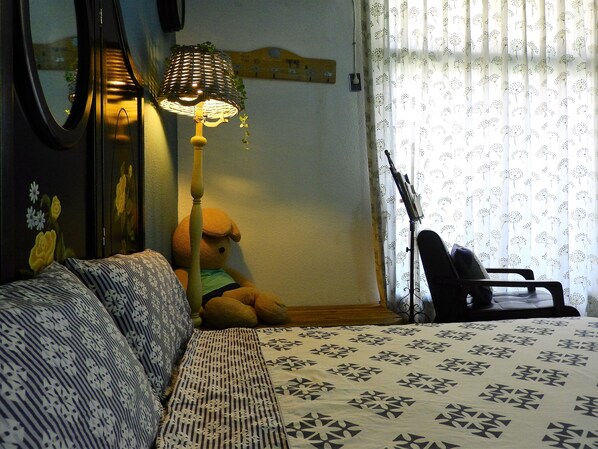 A room with a bed, a lamp, a teddy bear, and a guitar. - House 123 Lan (Tainan)
