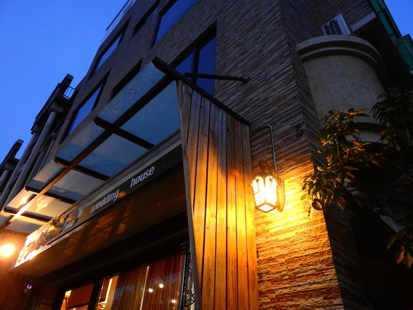 A building with a wooden facade, a glass entrance, and a sign that reads "house".