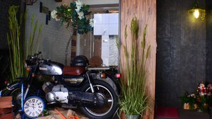 A motorcycle parked inside a building with a wooden interior, a clock, and decorative plants.