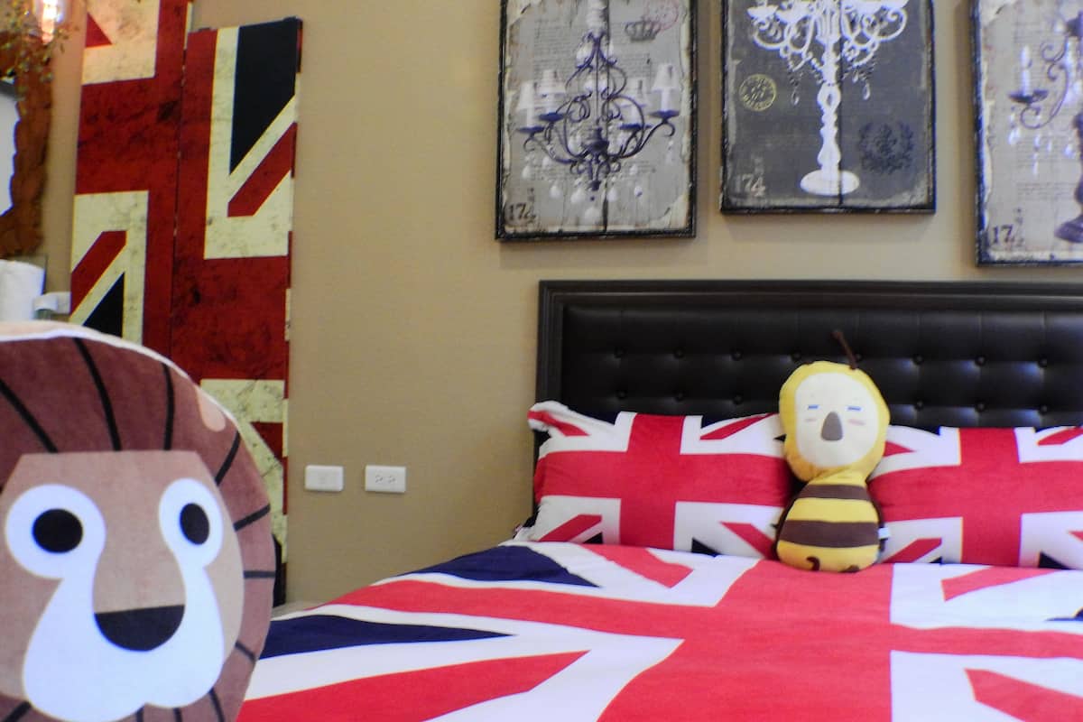A bedroom with a bed featuring a Union Jack pillow and a plush toy.
