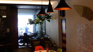 A dining area with a round table, orange chairs, and hanging pendant lights.