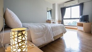 A modern bedroom with a large bed, bedside lamp, and a TV on a wooden stand. - Casa Asara (Bangkok)