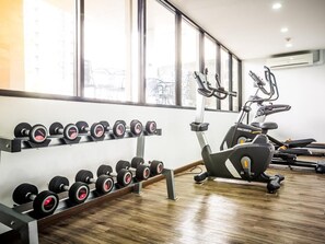 Una palestra con attrezzature per esercizi, tra cui manubri e un ellittica.