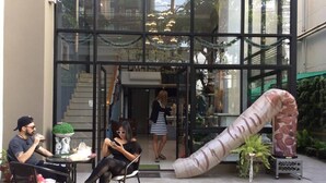 An outdoor seating area with tables and chairs, a staircase, and a large glass building in the background. - Casa Asara (Bangkok)
