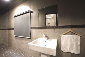 A bathroom with a white sink, a mirror, and a towel hanging on a rack.
