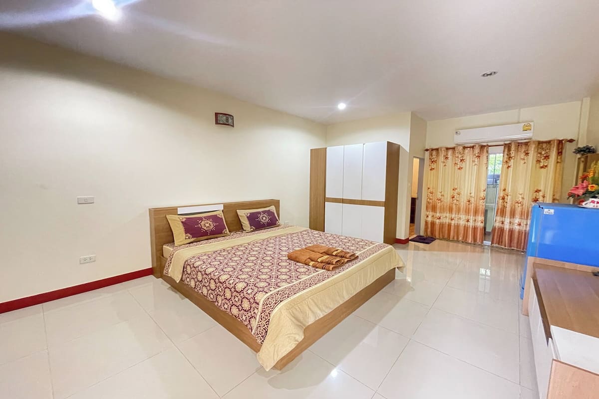 Un dormitorio con cama, armario, aire acondicionado y escritorio.