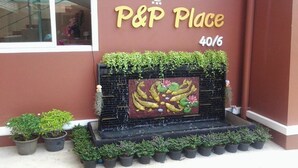 A building with a sign reading "P&P Place 40/6" and a decorative water feature with plants in front. - P&P Place (Kanchanaburi)