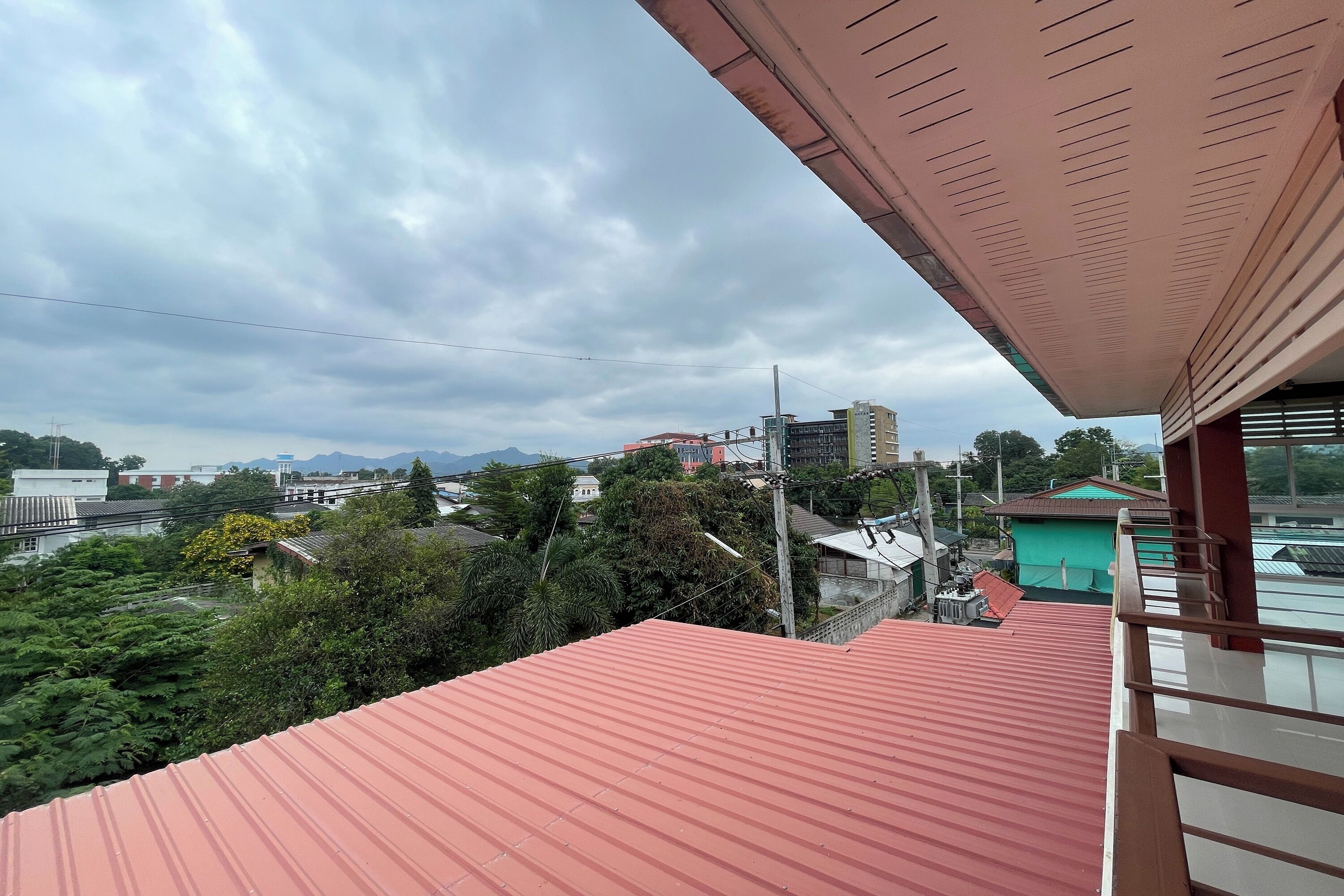 A red-roofed building with a balcony overlooking a cityscape.