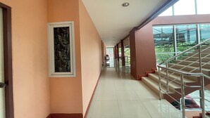 A corridor with a staircase on the right, a door on the left, and a framed artwork on the wall. - P&P Place (Kanchanaburi)