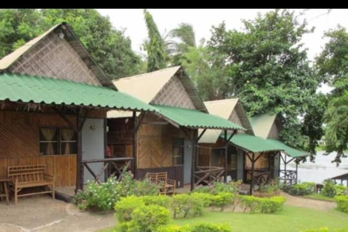 A row of wooden cabins with green roofs and wooden benches outside.