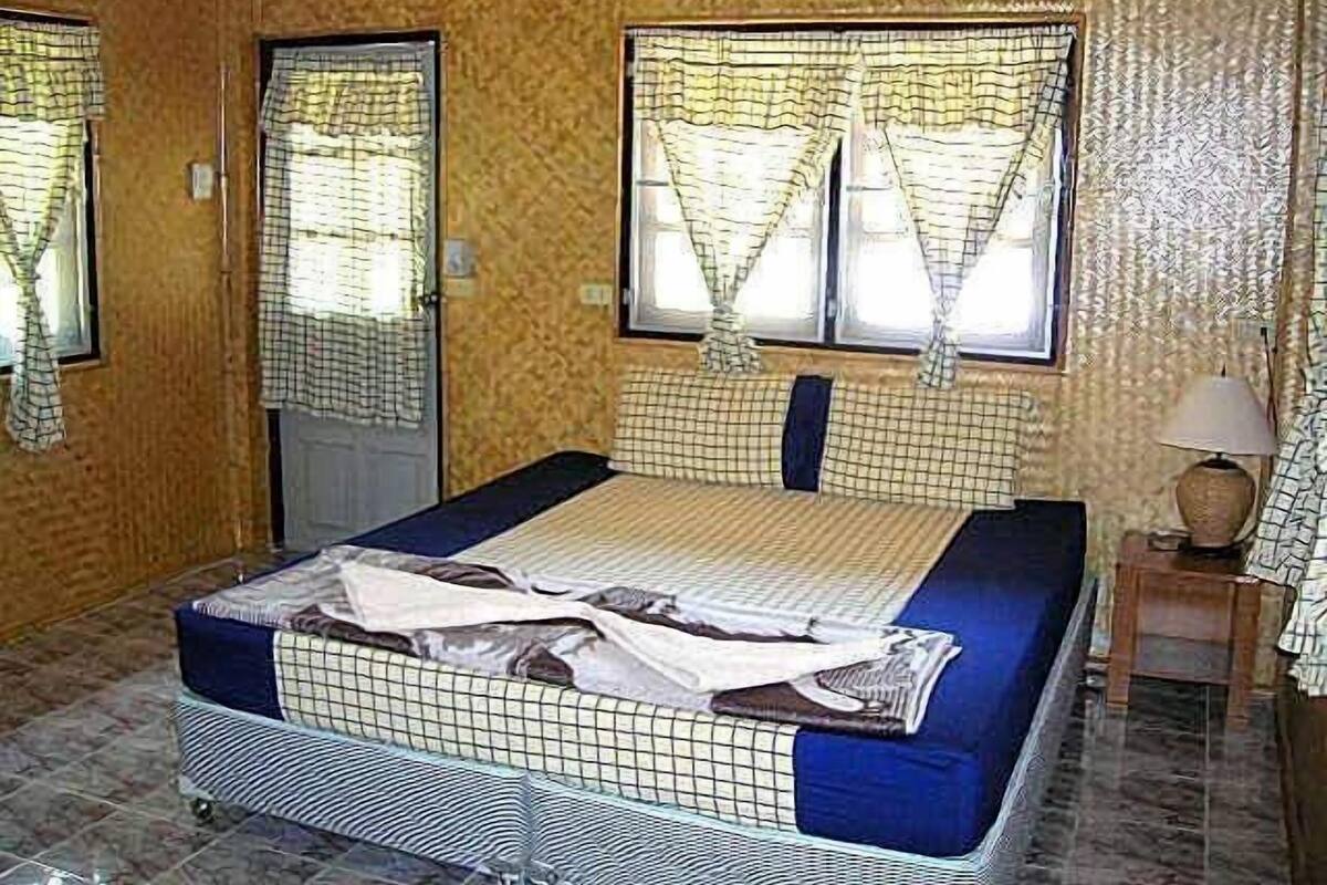 A room with a bed, a window with curtains, a lamp, and a door.