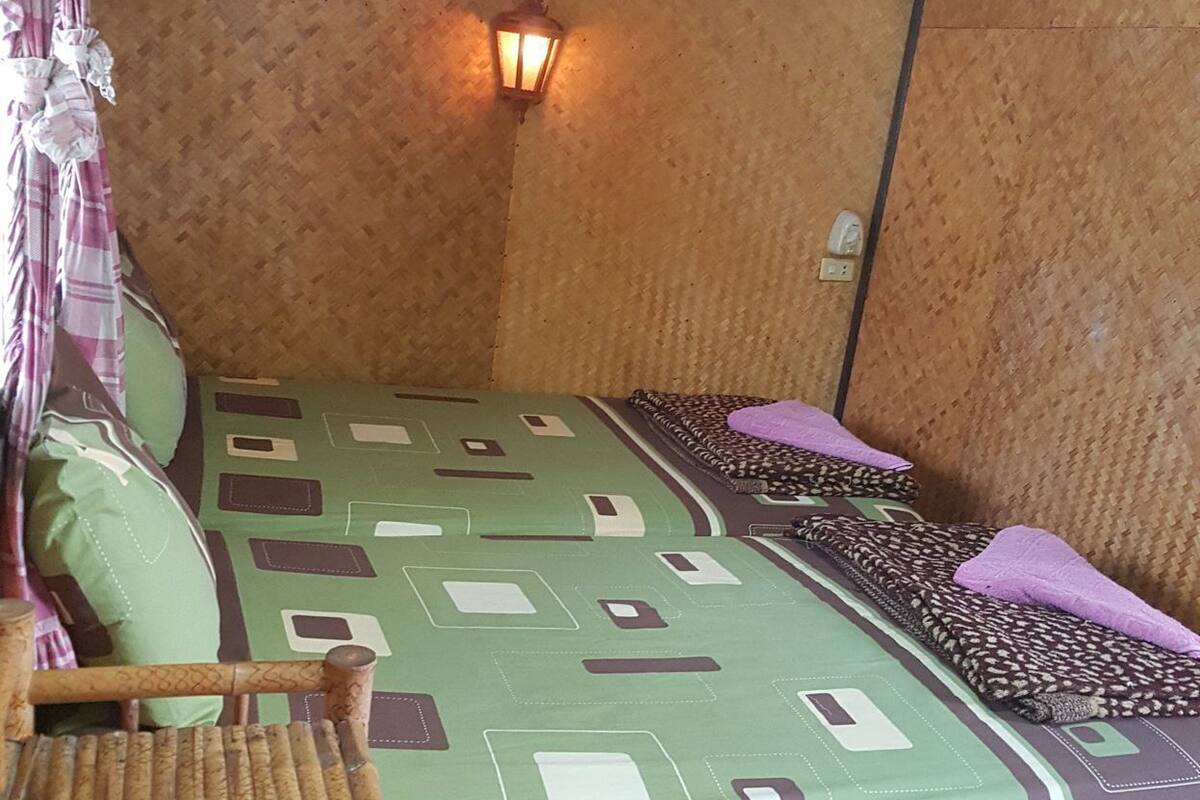 A room with a bed, a table, a chair, a wall-mounted light, and a power outlet.