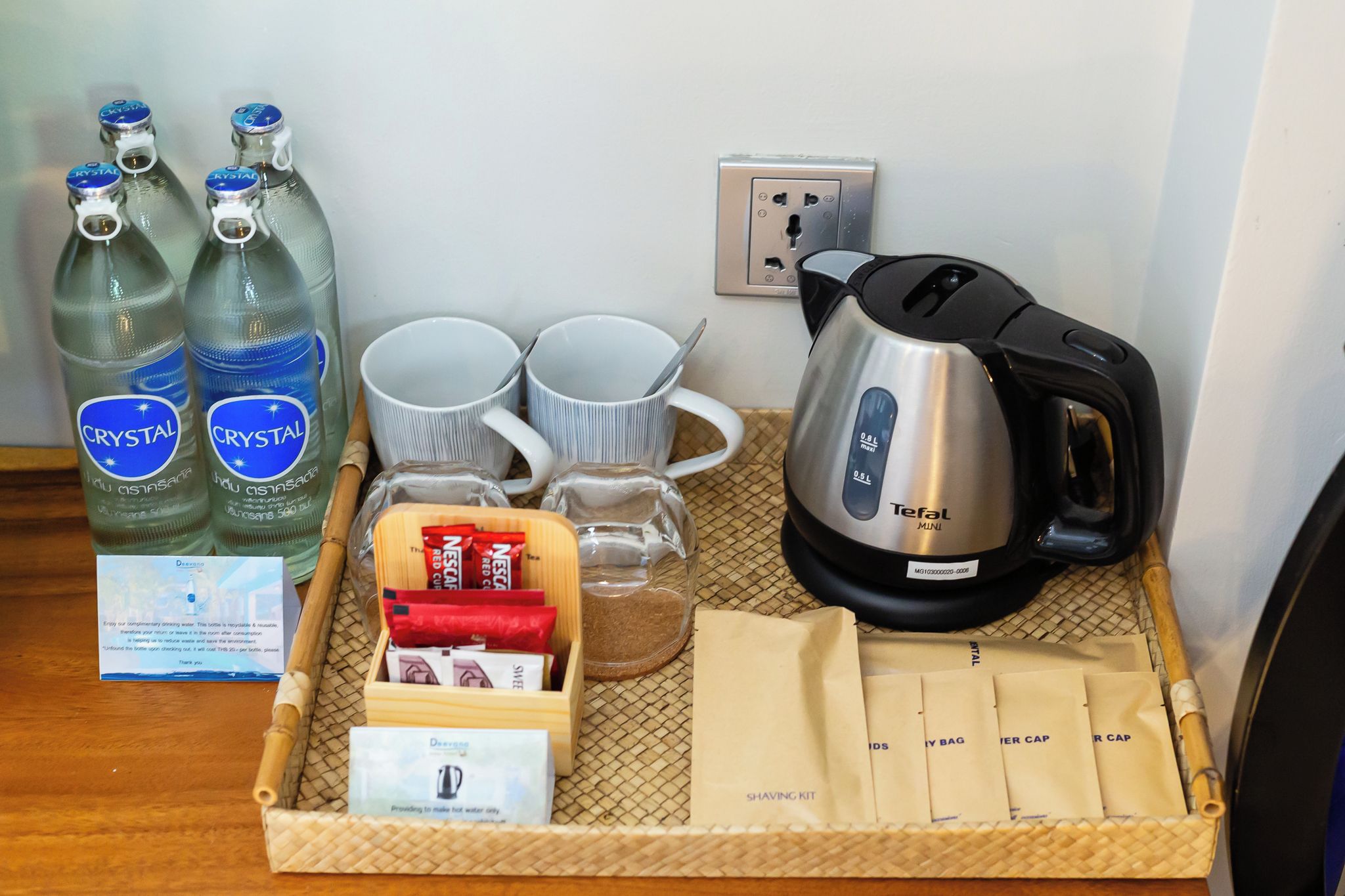 Una bandeja con botellas de agua, tazas de café, un hervidor, bolsitas de té y kits de afeitado.