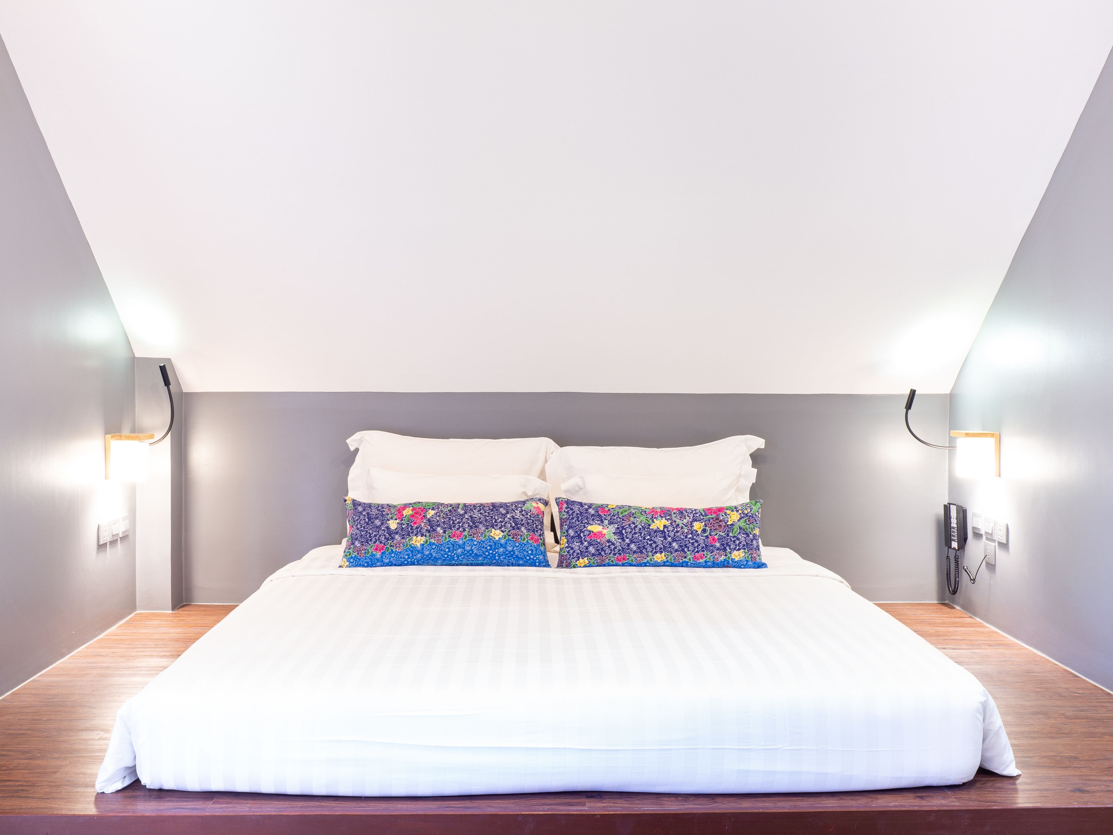 Una cama bien hecha con sábanas blancas y un cojín floral colorido.